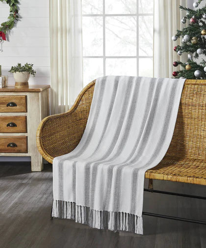 Striped throw blanket draped over a rattan chair in a cozy farmhouse living room — Pillows, Throws & Textiles at Simply Serenity